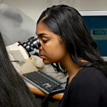 A member of Teen Voices studies HPV under a microscope. 